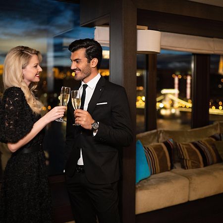 Intercontinental Budapest By Ihg Esterno foto The photo depicts a couple celebrating a special moment. The woman is wearing a stylish black dress and is holding a glass of champagne, while the man is dressed in a formal black suit and also holding a glass. They are smiling at each other in a war