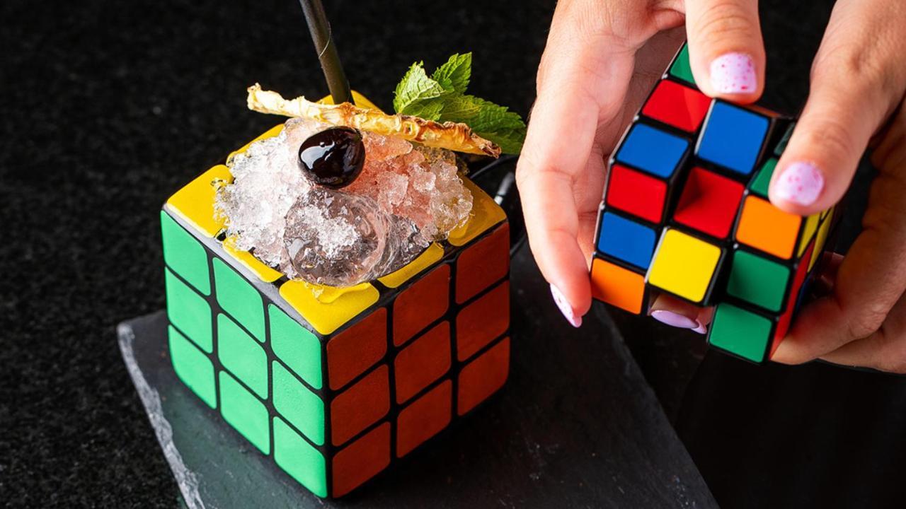 Intercontinental Budapest By Ihg Esterno foto The photo depicts two Rubik's Cube-inspired containers. One is filled with crushed ice and garnished with a sprig of mint and a dark cherry on top. A straw is inserted into the ice-filled cube. The other cube is being held by a hand, showing its colo