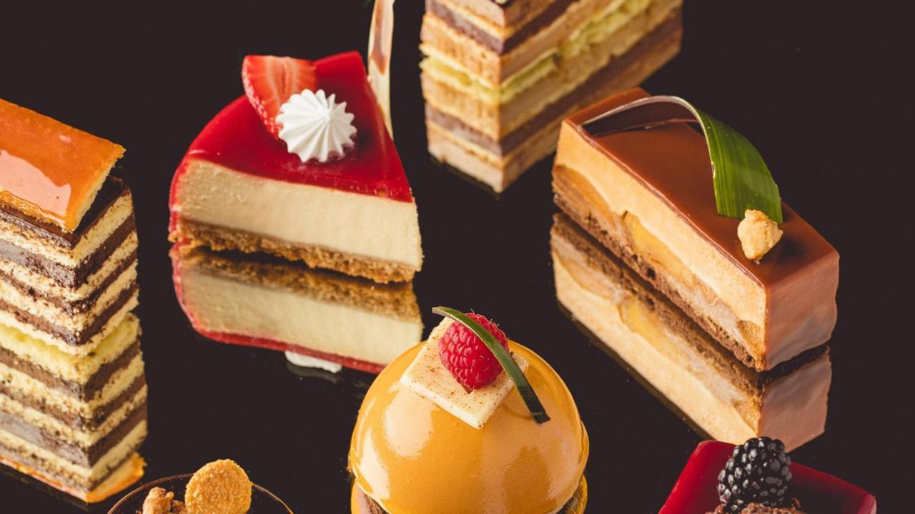 Intercontinental Budapest By Ihg Esterno foto The photo showcases an assortment of elegant desserts, including various types of cake slices and a round mousse-like dessert. Notable features include:

1. **Cheesecake slice** with a smooth cream layer, topped with a small dollop of whipped cream a
