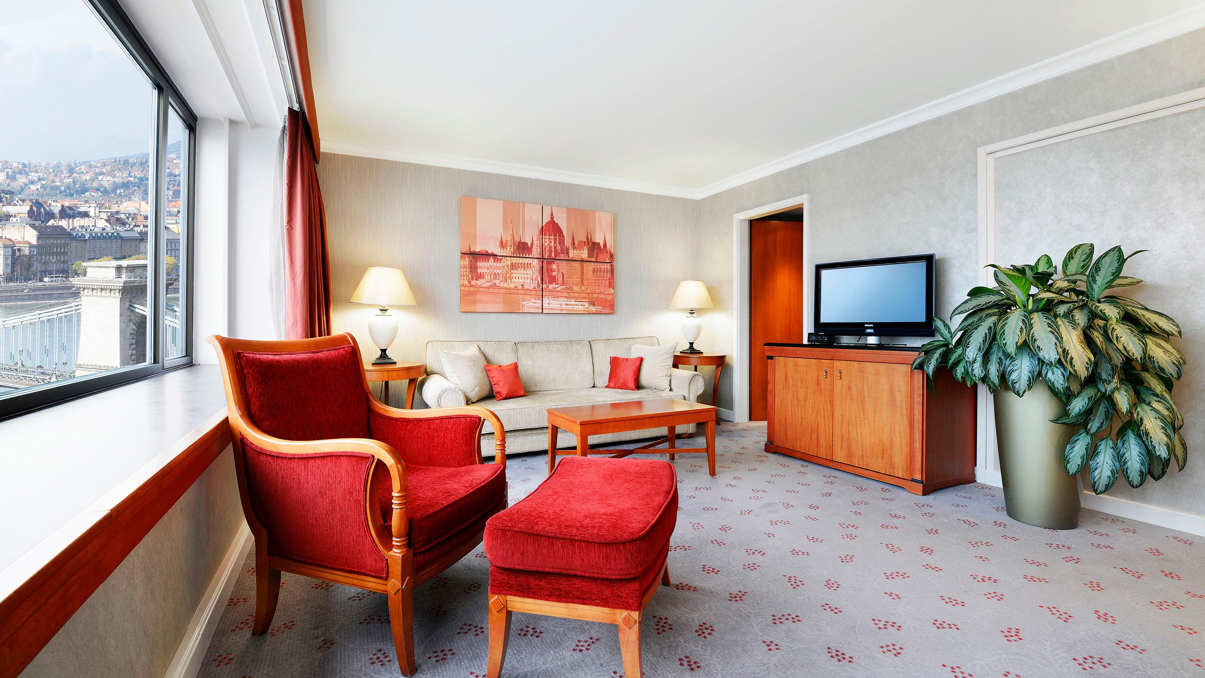 Intercontinental Budapest By Ihg Esterno foto The photo shows a cozy living space with a warm and inviting atmosphere. There is a comfortable light-colored sofa adorned with small pillows, positioned against a wall. Next to the sofa, two red armchairs add a pop of color, complemented by a matchi