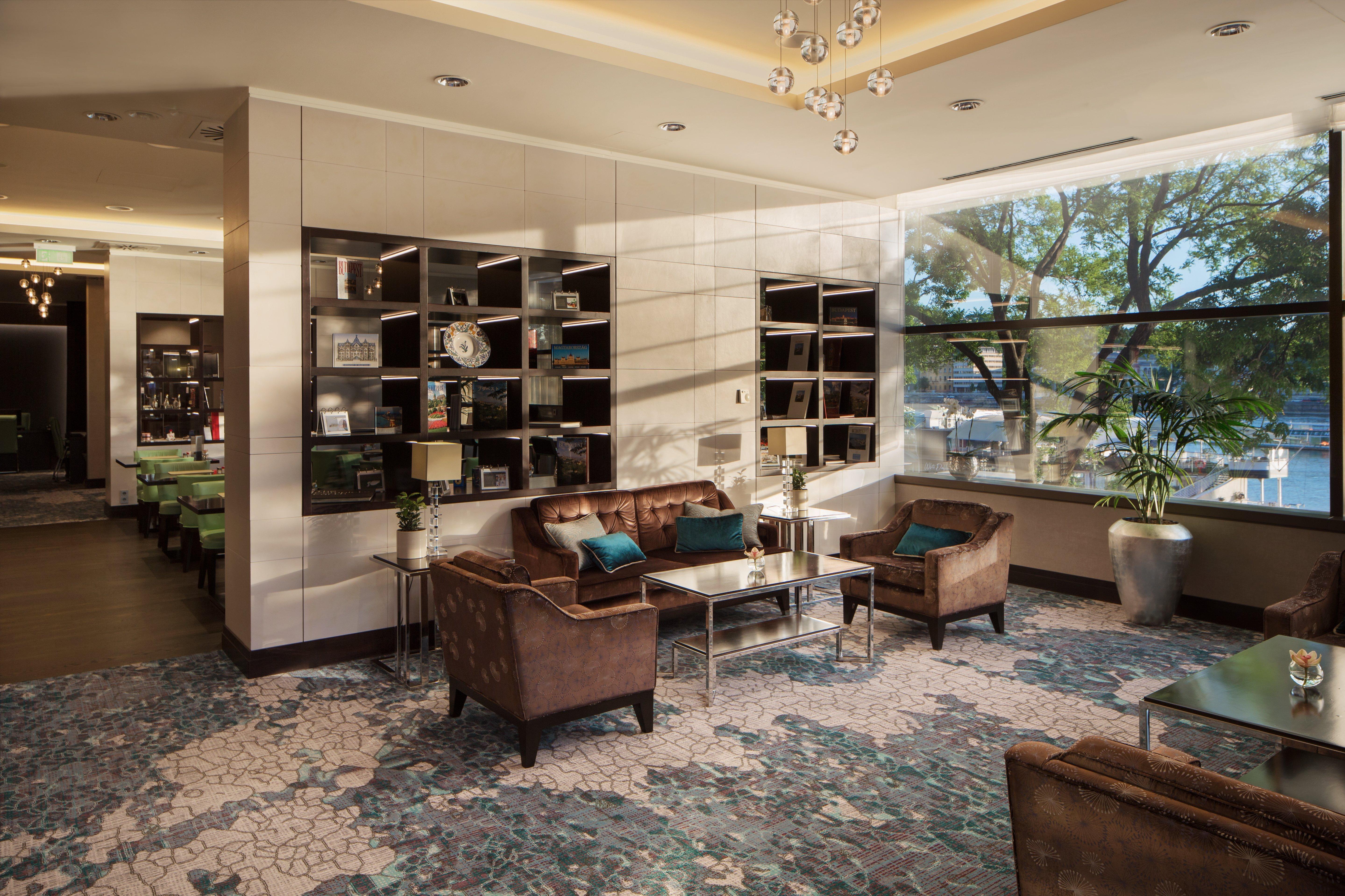 Intercontinental Budapest By Ihg Esterno foto The photo depicts a modern lounge area featuring comfortable brown leather seating, including two armchairs and a sofa, arranged around a glass coffee table. A decorative shelf unit against the wall displays various items, adding a touch of elegance 