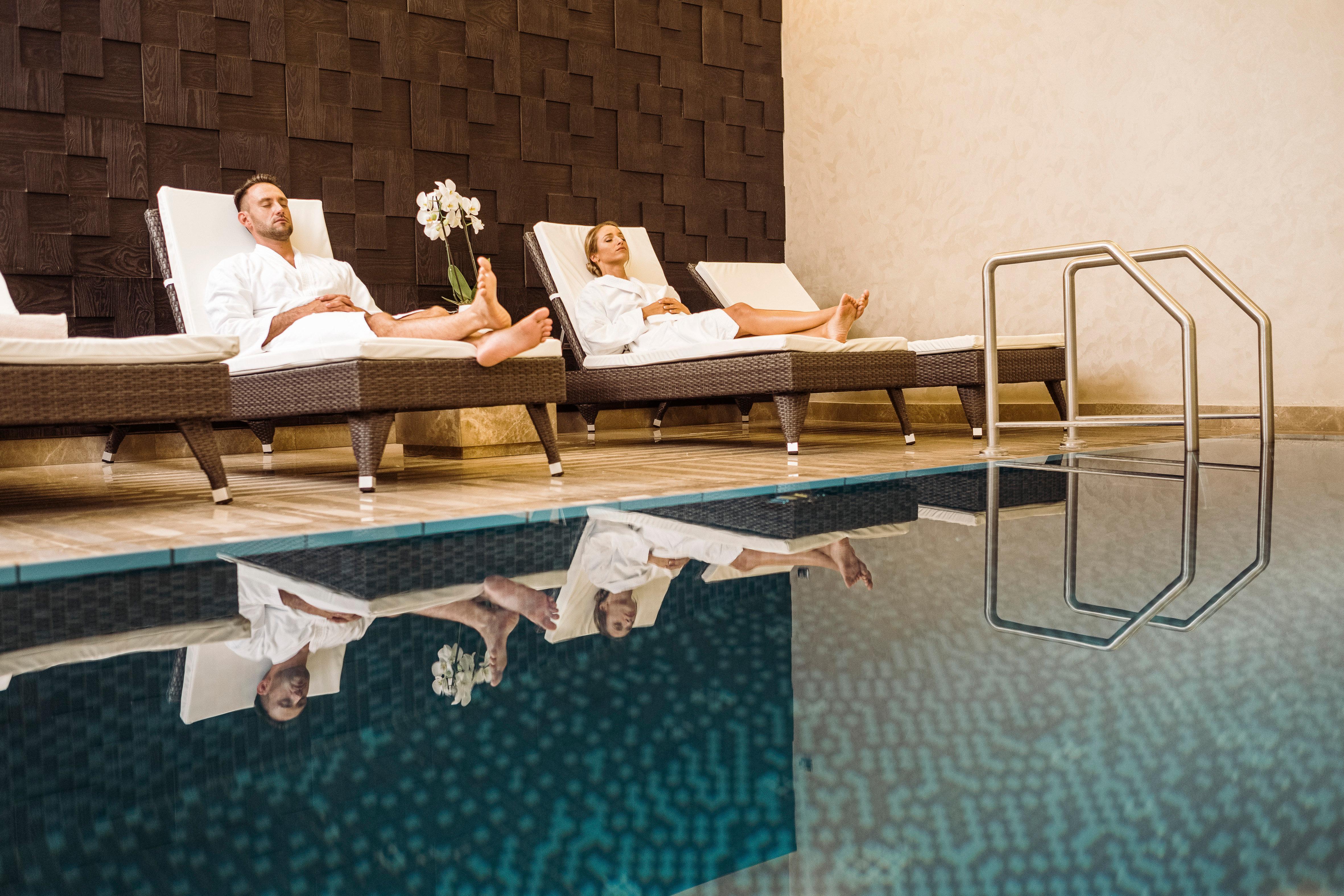 Intercontinental Budapest By Ihg Esterno foto The photo depicts a serene spa environment featuring two individuals lounging on comfortable deck chairs. They are dressed in white robes, suggesting a relaxing atmosphere. In the background, there is a wooden wall, and next to them, there are potted