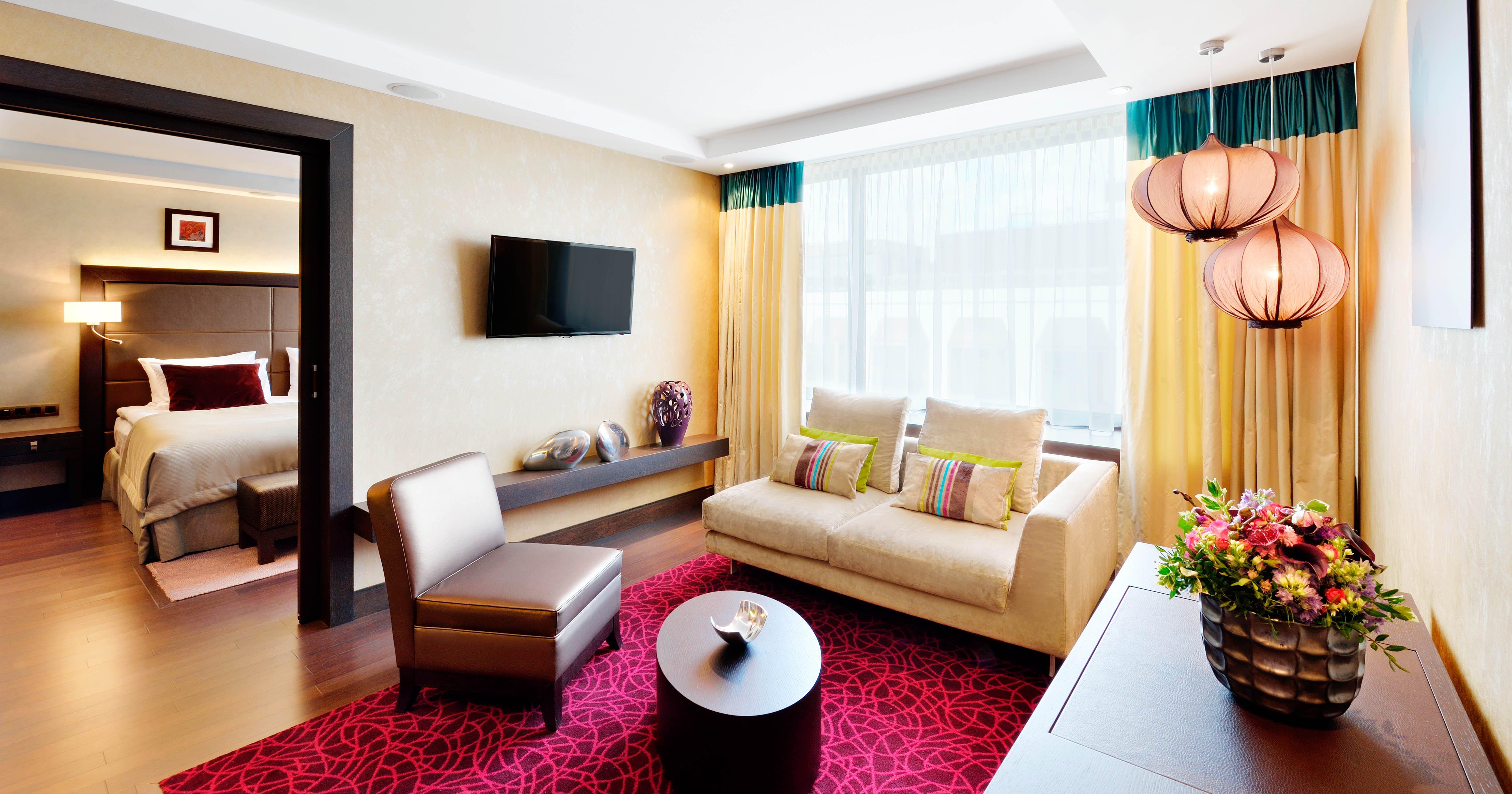 Intercontinental Budapest By Ihg Esterno foto The photo shows a modern living area with a comfortable atmosphere. There is a light-colored sofa adorned with colorful throw pillows, paired with a dark, stylish chair. A round coffee table is positioned in the center, and a decorative item sits on 