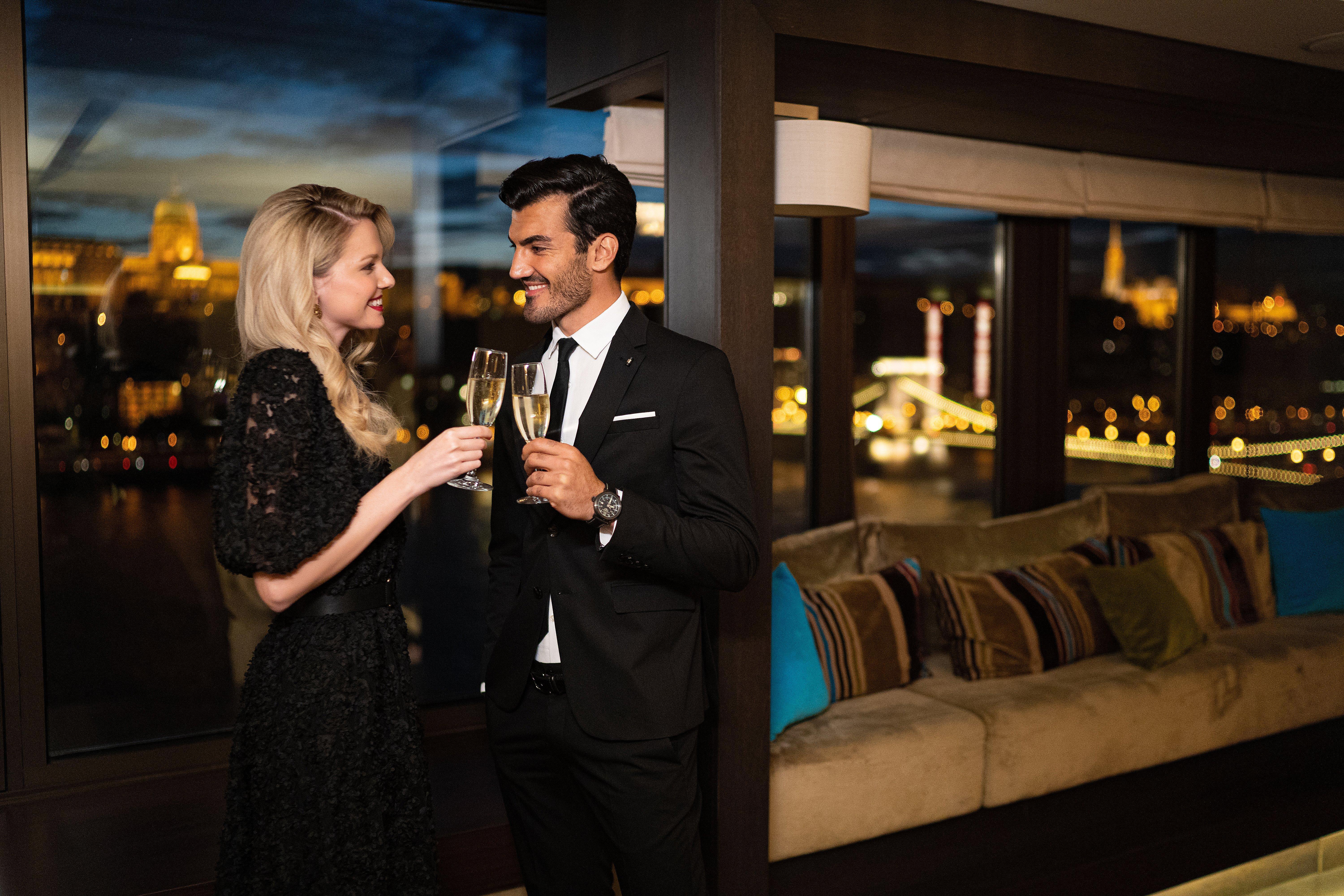 Intercontinental Budapest By Ihg Esterno foto The photo depicts a couple celebrating a special moment. The woman is wearing a stylish black dress and is holding a glass of champagne, while the man is dressed in a formal black suit and also holding a glass. They are smiling at each other in a war